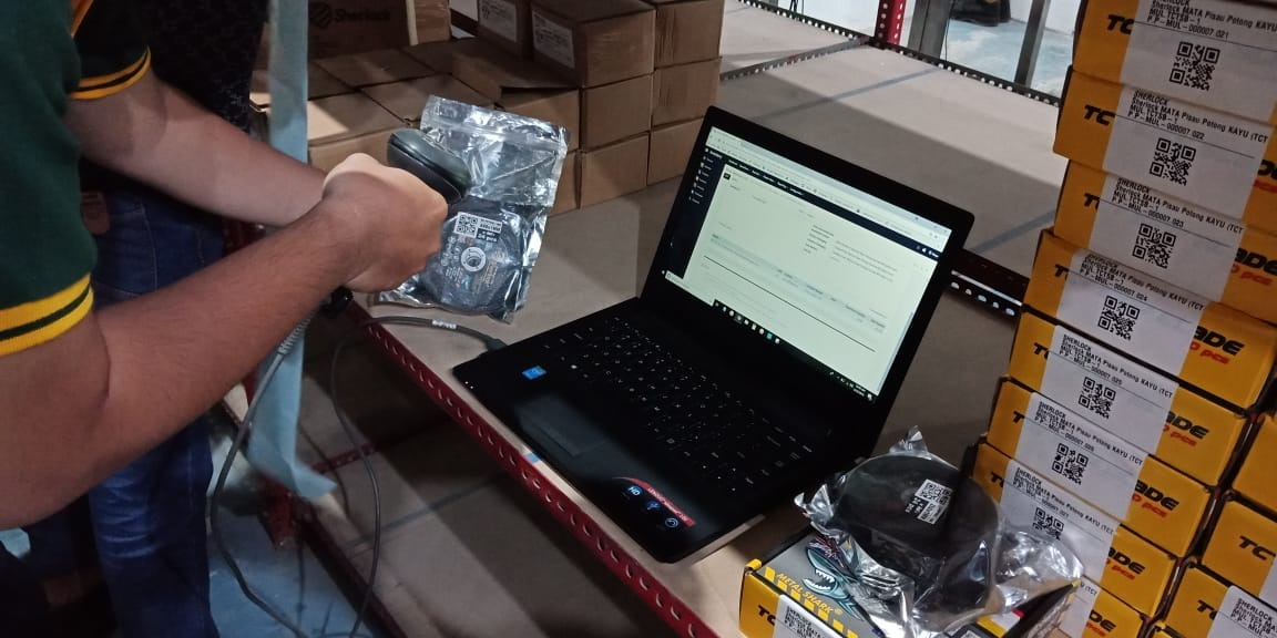 Petugas gudang SherlockTools memindai perkakas dengan barcode scanner di samping laptop yang menampilkan sistem inventori